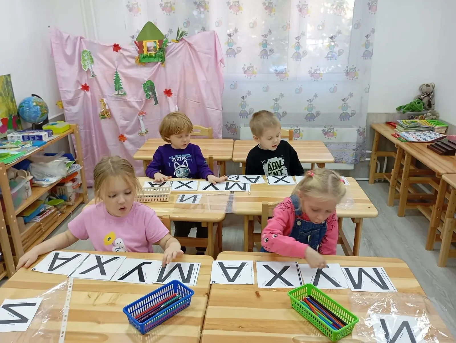 Дети изучают карточки с буквами за партами